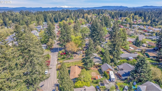 view of property location with a heavily wooded area, a mountainous background, and nearby suburban area