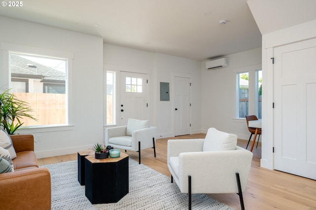 319 N Holland St, Portland, OR 97217 - living room featuring a wall unit AC, electric panel, light wood-style flooring, and baseboards