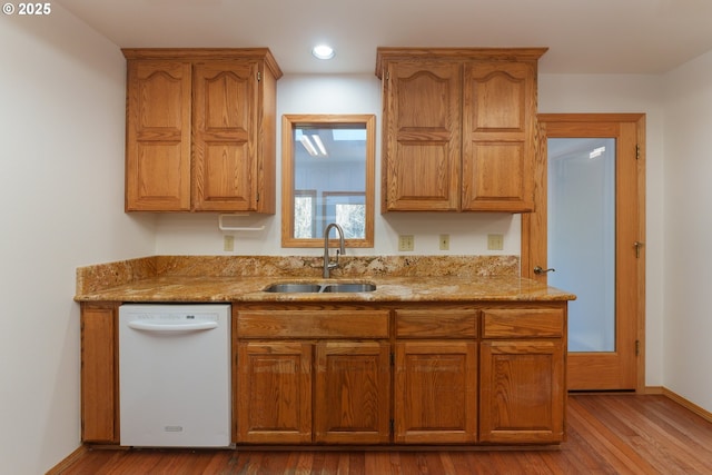 kitchen with white dishwasher, light hardwood / wood-style floors, sink, and light stone countertops