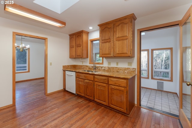 kitchen with plenty of natural light, dishwasher, sink, and light wood-type flooring