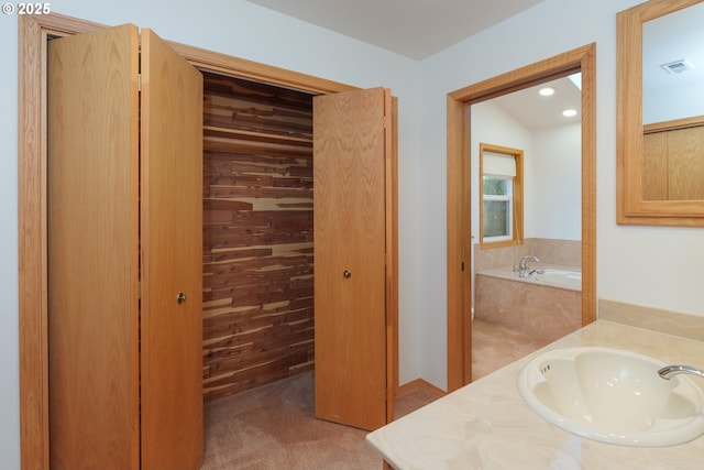 bathroom featuring a relaxing tiled tub, vanity, and wood walls