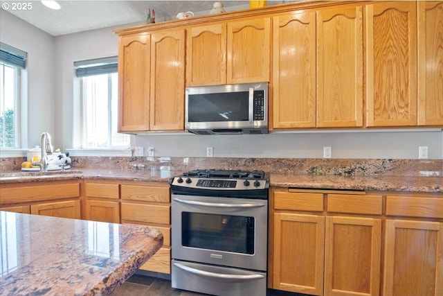 kitchen featuring stainless steel appliances, light stone countertops, and sink