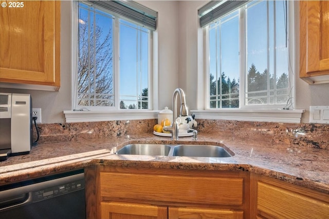 kitchen with black dishwasher, sink, and light stone counters