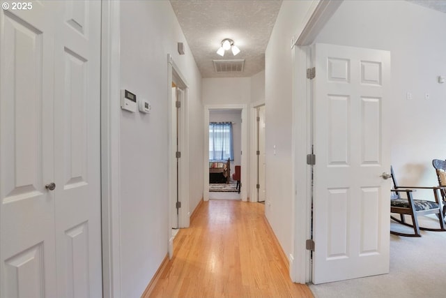 hall featuring light hardwood / wood-style floors and a textured ceiling