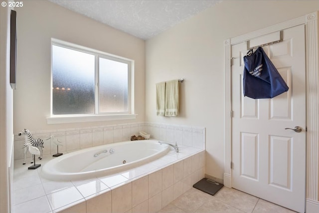 bathroom with tile patterned flooring, a relaxing tiled tub, and a textured ceiling