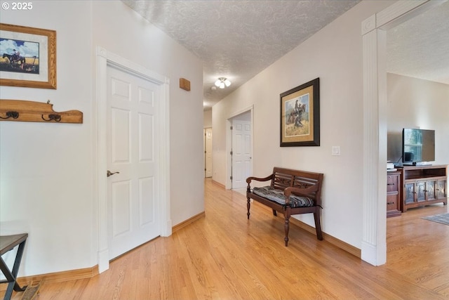 hallway featuring light hardwood / wood-style floors and a textured ceiling