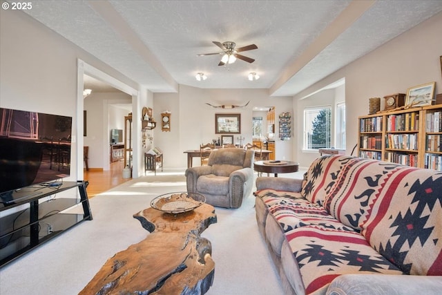 carpeted living room featuring ceiling fan and a textured ceiling