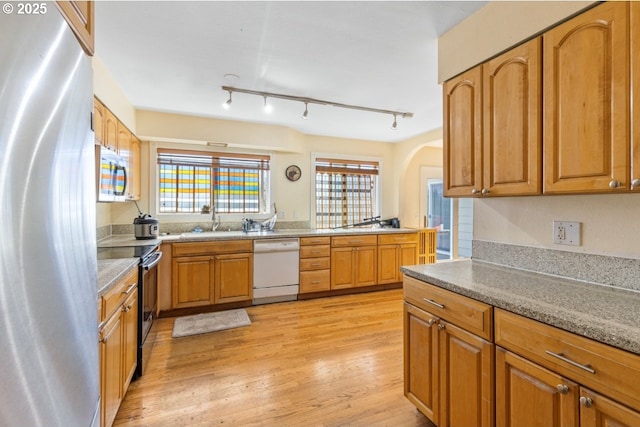 31958 J P W Rd, Scappoose, OR 97056 - kitchen with stainless steel appliances, a sink, light wood-style floors, arched walkways, and brown cabinets