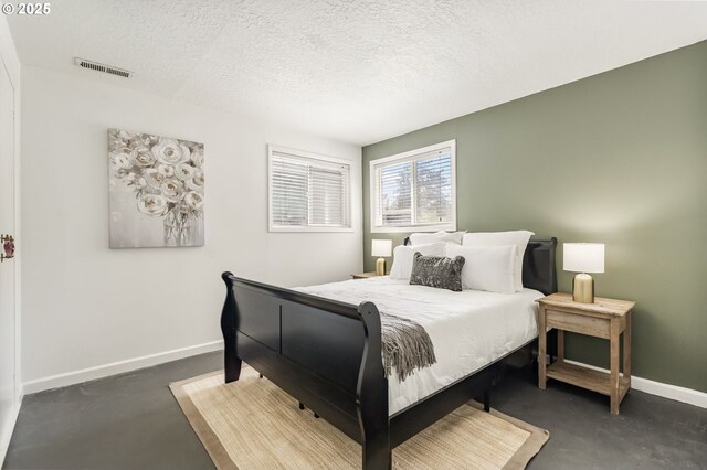 bedroom with finished concrete flooring, baseboards, a textured ceiling, and visible vents