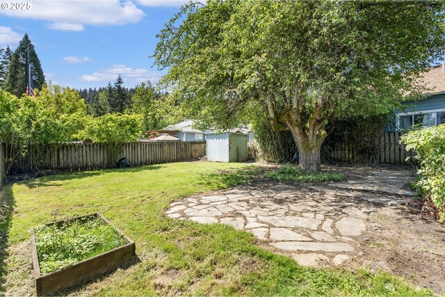 view of yard featuring a storage shed, an outbuilding, a fenced backyard, and a vegetable garden