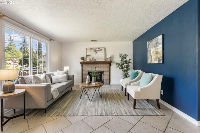living room featuring a textured ceiling, visible vents, a brick fireplace, baseboards, and light tile patterned flooring