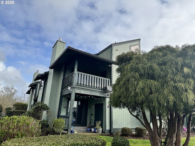 back of property with a chimney and a balcony