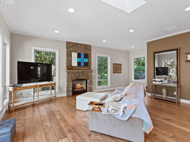 living area featuring plenty of natural light, a stone fireplace, a skylight, and light wood finished floors