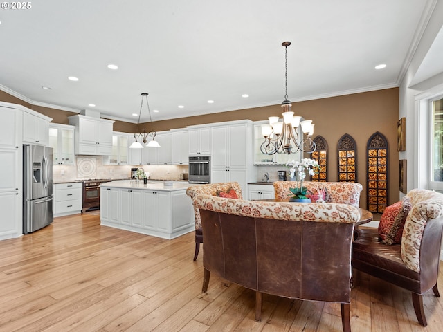 dining room with an inviting chandelier, light wood-style flooring, and ornamental molding