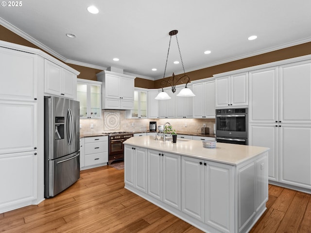 kitchen featuring a sink, white cabinets, crown molding, double oven, and stainless steel fridge