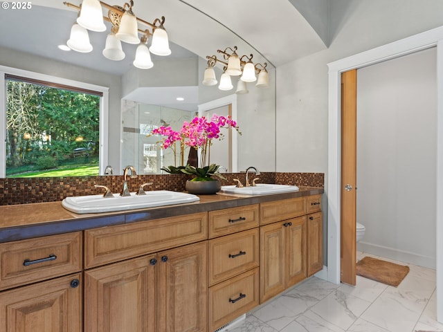 full bath featuring double vanity, marble finish floor, toilet, and a sink