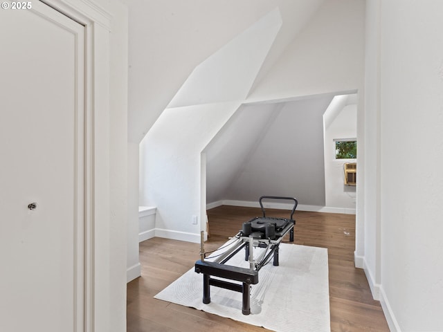 exercise room with lofted ceiling, wood finished floors, and baseboards