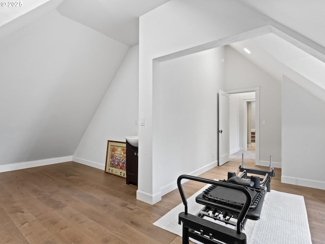 workout room with lofted ceiling, baseboards, and light wood-type flooring