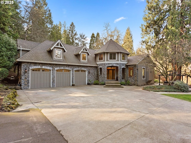 view of front of house featuring stone siding, an attached garage, a shingled roof, and driveway