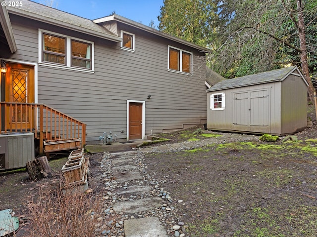 back of property with a storage shed, central air condition unit, and an outbuilding