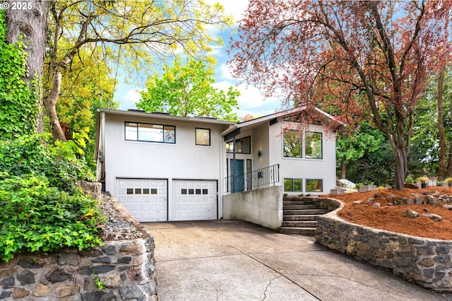 view of front facade featuring a garage, concrete driveway, stucco siding, and stairway