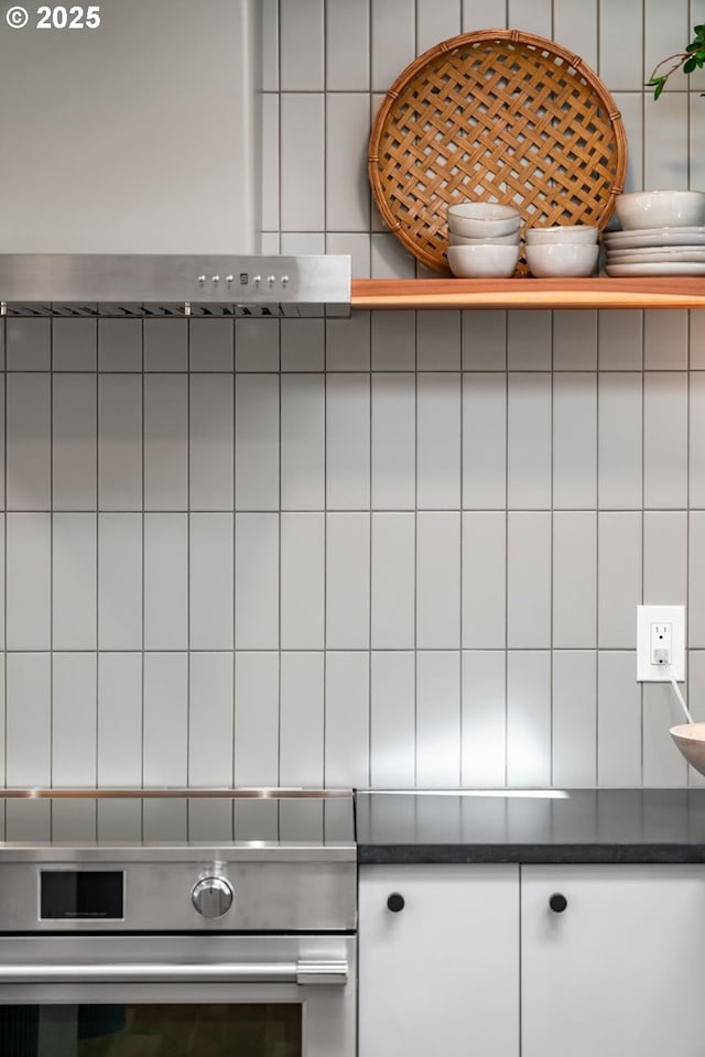 kitchen view of dark countertops, white cabinets, and stainless steel oven