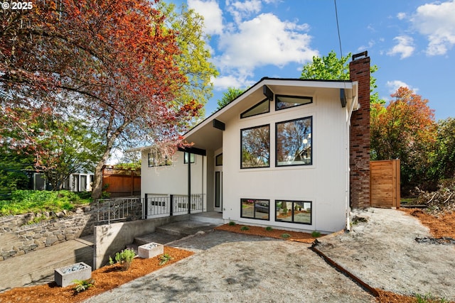 view of front of property featuring a chimney, fence, and a patio