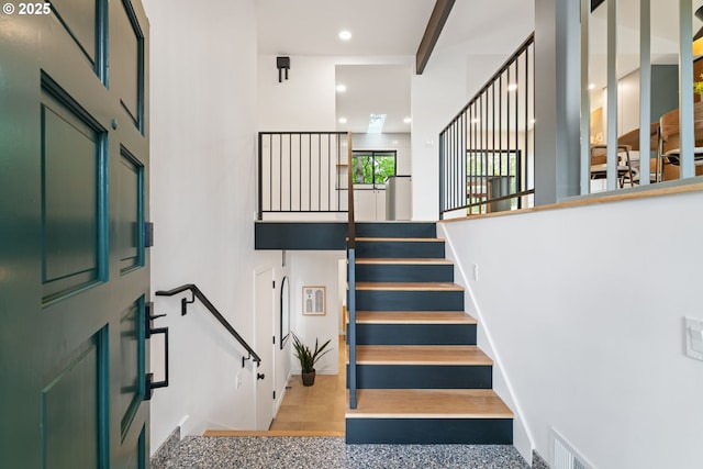 stairs with a towering ceiling and recessed lighting