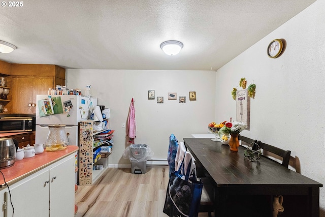 kitchen with baseboard heating, light hardwood / wood-style floors, a textured ceiling, and white refrigerator