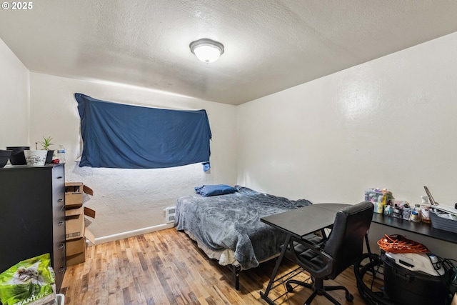 bedroom with hardwood / wood-style floors and a textured ceiling