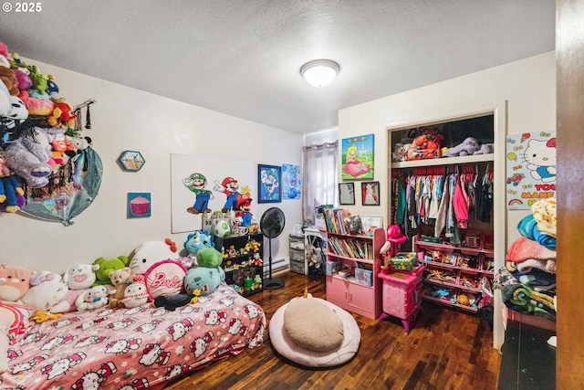 bedroom featuring a baseboard heating unit, a textured ceiling, dark hardwood / wood-style flooring, and a closet