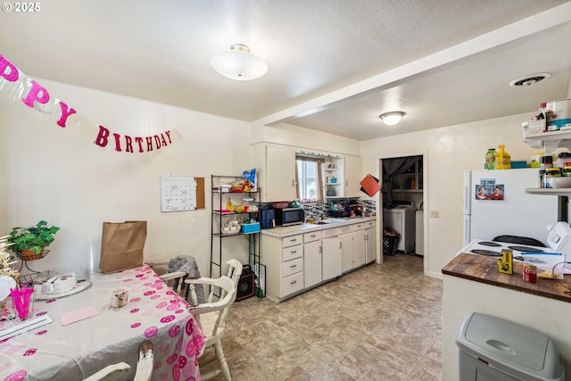 kitchen featuring separate washer and dryer, a textured ceiling, white cabinets, and white fridge