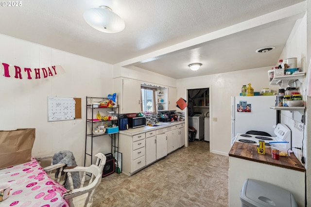 kitchen with white cabinetry, white appliances, washer and clothes dryer, and a textured ceiling