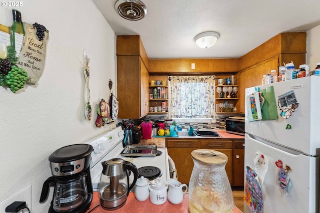 kitchen featuring sink, white appliances, and a textured ceiling