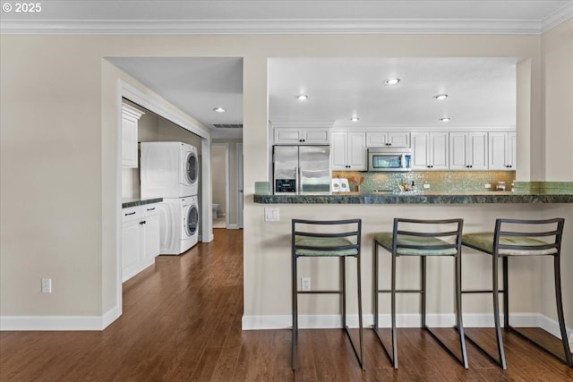 10620 SW Highland Dr, Portland, OR 97224 - kitchen with appliances with stainless steel finishes, estacked washer and dryer, a breakfast bar area, dark wood finished floors, and white cabinets