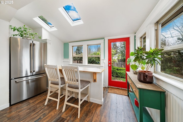 interior space with baseboards, lofted ceiling with skylight, and dark wood finished floors