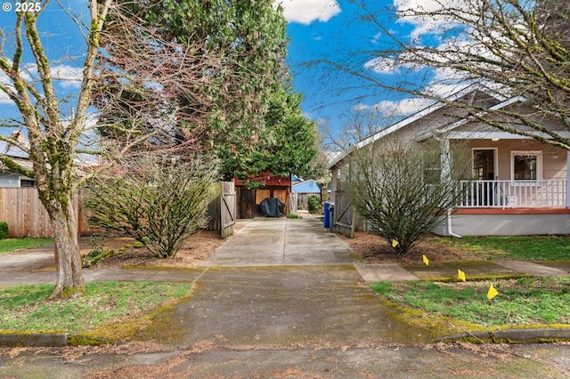 view of property exterior with covered porch, driveway, and fence