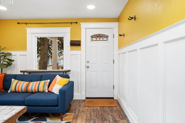 interior space with dark wood-type flooring, a decorative wall, recessed lighting, and wainscoting