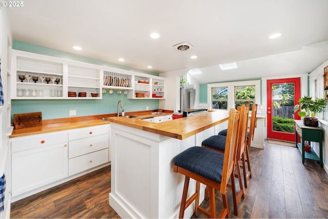 kitchen featuring a kitchen island, open shelves, dark wood-style flooring, a sink, and butcher block counters