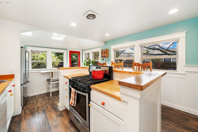 kitchen with visible vents, wooden counters, a wainscoted wall, appliances with stainless steel finishes, and dark wood-style flooring