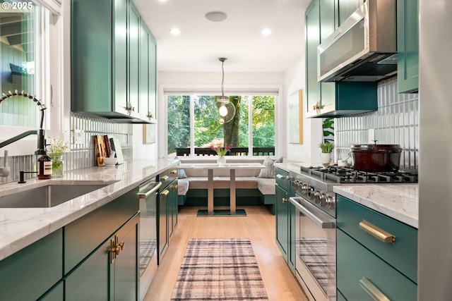 5431 SW Alfred St, Portland, OR 97219 - kitchen featuring green cabinets, stainless steel appliances, a sink, light wood-style flooring, and decorative backsplash