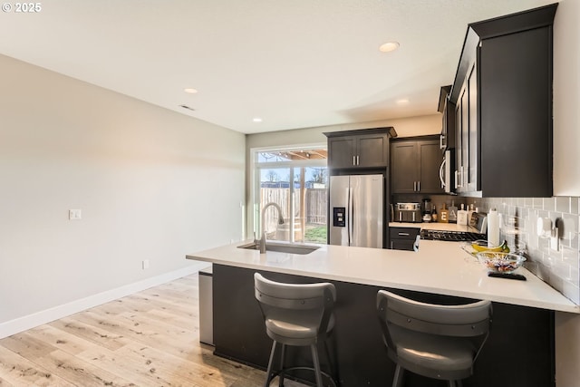 kitchen featuring sink, a breakfast bar area, backsplash, kitchen peninsula, and stainless steel appliances