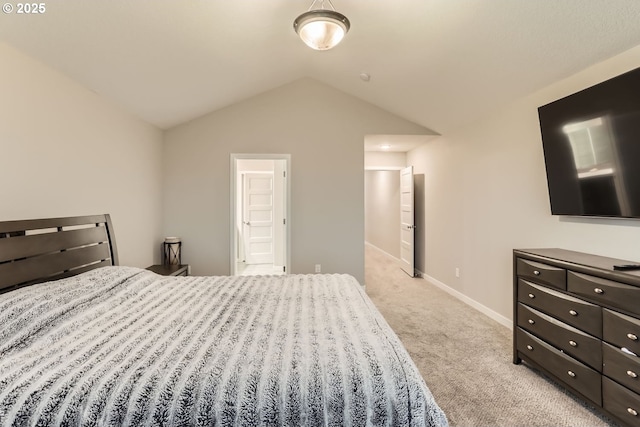 bedroom featuring ensuite bath, vaulted ceiling, and light colored carpet