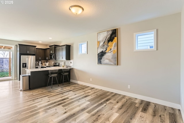 kitchen with stainless steel appliances, light hardwood / wood-style flooring, a kitchen breakfast bar, and kitchen peninsula