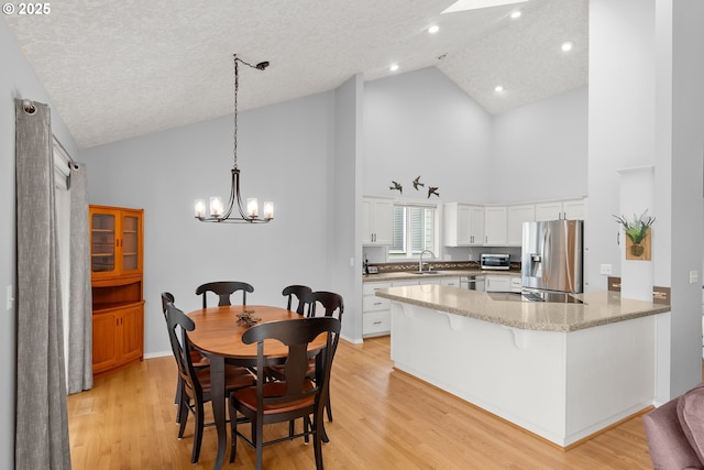 7409 SW Locust St, Portland, OR 97223 - kitchen with stainless steel appliances, high vaulted ceiling, a peninsula, white cabinets, and a chandelier
