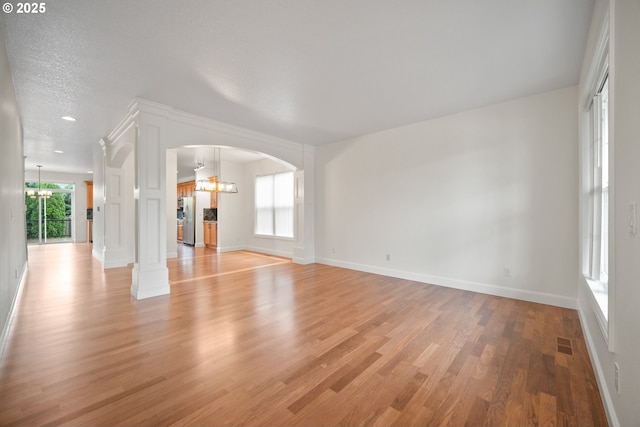 2530 NW 22nd Ave, Camas, WA 98607 - unfurnished living room featuring a chandelier, light wood finished floors, baseboards, and arched walkways