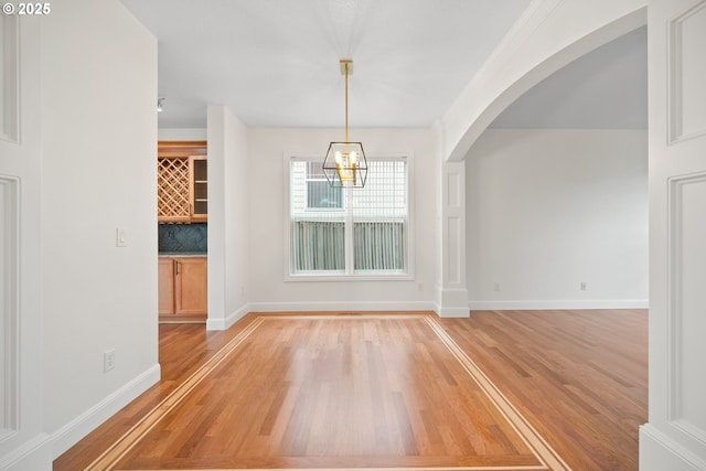 2530 NW 22nd Ave, Camas, WA 98607 - unfurnished dining area featuring light wood-type flooring, a chandelier, baseboards, and arched walkways