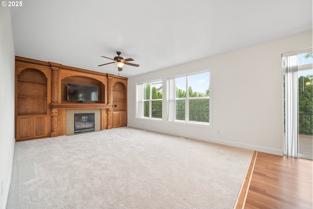 2530 NW 22nd Ave, Camas, WA 98607 - unfurnished living room with a tiled fireplace, a ceiling fan, baseboards, light wood-type flooring, and light carpet