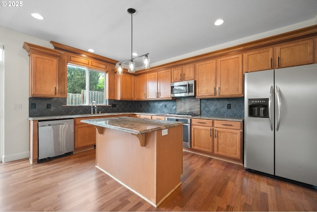 2530 NW 22nd Ave, Camas, WA 98607 - kitchen with stainless steel appliances, wood finished floors, brown cabinets, a kitchen island, and recessed lighting