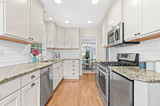 6611 SE 40th Ave, Portland, OR 97202 - kitchen featuring stainless steel appliances, light wood-type flooring, tasteful backsplash, white cabinetry, and recessed lighting